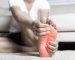 Foot pain, Asian woman feeling pain in her foot at home, female suffering from feet ache use hand massage relax muscle from soles in home interior, Healthcare problems and podiatry medical concept